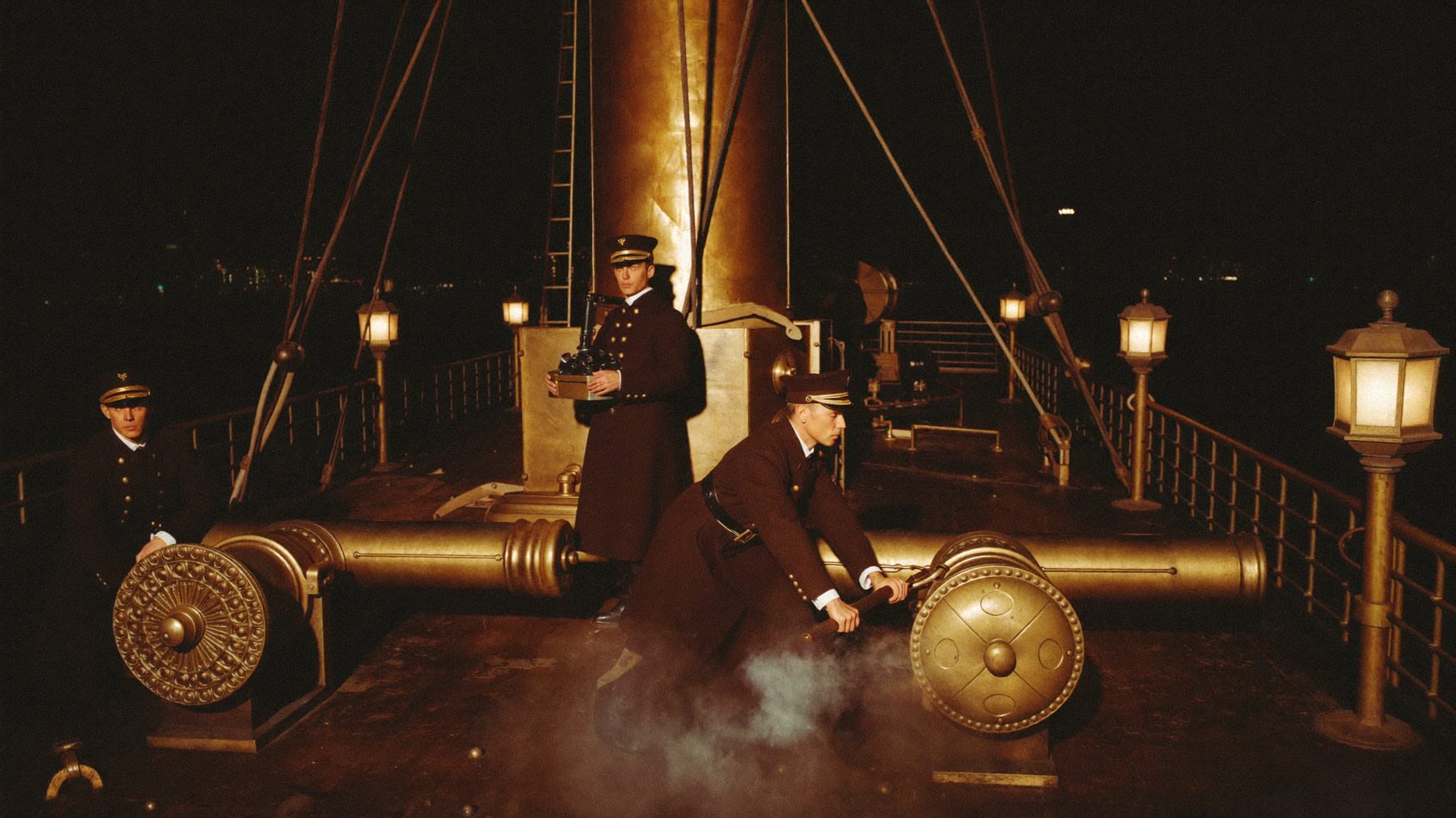 Sailors in navy-brown wool greatcoats working cannon drill in lantern light.
