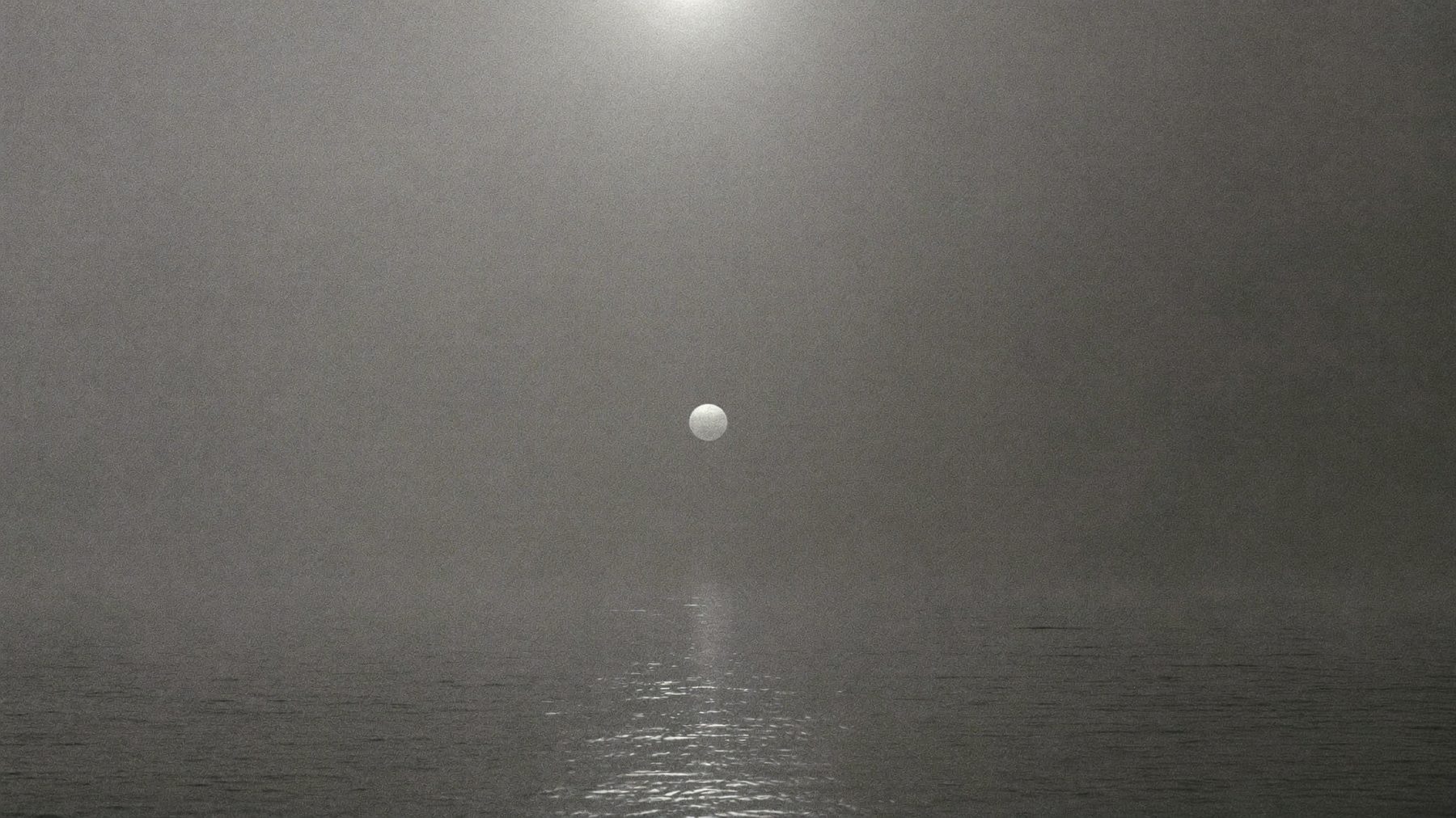 Glass-calm gray water stretching into a wall of heavy sea fog.